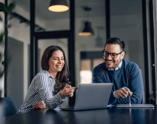 Two bilingual Tax Genius Pro professionals smiling as they review taxes together on a laptop